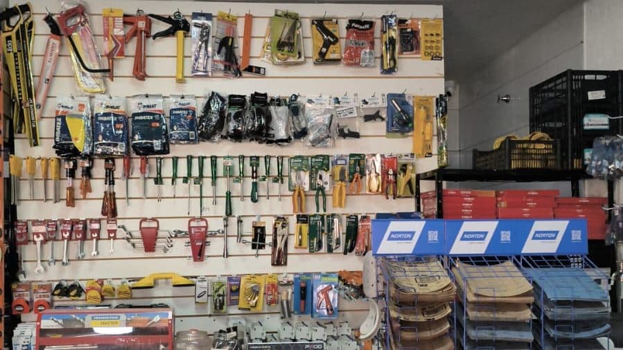 Parede de ferramentas manuais — serrotes, chaves de fenda, alicates e pistolas — no balcão da Progresso Materiais de Construção em Aparecida de Goiânia